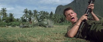 Movie still from “Casualties of War” (1989), directed by Brian De Palma – Two men laying in the grass near some palm trees; Medium shot, Low angle