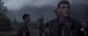 Movie still from “Casualties of War” (1989), directed by Brian De Palma – A group of men standing next to each other on top of a field; Close Up shot, Over the shoulder angle