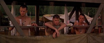 Movie still from “Casualties of War” (1989), directed by Brian De Palma – A shirtless man leaning on a railing in the rain; Medium shot, Low angle