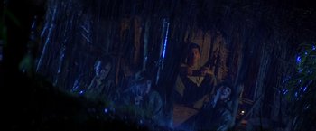 Movie still from “Casualties of War” (1989), directed by Brian De Palma – A group of people sitting in a dark forest; Wide shot, Low angle
