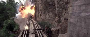Movie still from “Casualties of War” (1989), directed by Brian De Palma – A group of soldiers are standing next to a train track; Wide shot, High angle