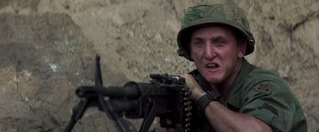Movie still from “Casualties of War” (1989), directed by Brian De Palma – A man with a helmet on and a gun in his hand; Close Up shot, Low angle