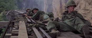 Movie still from “Casualties of War” (1989), directed by Brian De Palma – A group of men laying on top of a train track; Wide shot, High angle