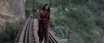 Movie still from “Casualties of War” (1989), directed by Brian De Palma – A woman with blood all over her face walking on a train track; Wide shot, High angle
