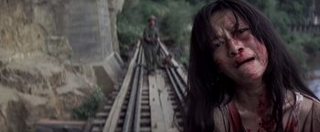 Movie still from “Casualties of War” (1989), directed by Brian De Palma – A woman standing on a train track next to a man sitting on a bench; Close Up shot, High angle