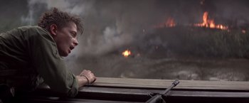 Movie still from “Casualties of War” (1989), directed by Brian De Palma – A man leaning on a rail looking out at a fire; Close Up shot, Over the shoulder angle