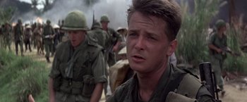Movie still from “Casualties of War” (1989), directed by Brian De Palma – A man in fatigues is standing in front of a group of soldiers; Close Up shot, Low angle