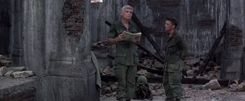 Movie still from “Casualties of War” (1989), directed by Brian De Palma – A man in a military uniform reading a newspaper; Medium shot, Over the shoulder angle
