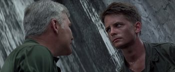 Movie still from “Casualties of War” (1989), directed by Brian De Palma – Two men are facing each other in front of a wall; Close Up shot, Over the shoulder angle