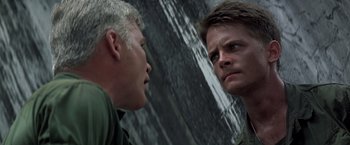 Movie still from “Casualties of War” (1989), directed by Brian De Palma – Two men are facing each other in front of a waterfall; Close Up shot, Over the shoulder angle