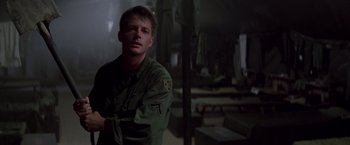 Movie still from “Casualties of War” (1989), directed by Brian De Palma – A man standing in a room wearing a green uniform; Medium shot, Low angle