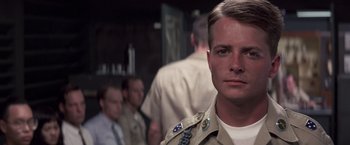 Movie still from “Casualties of War” (1989), directed by Brian De Palma – A man in a military uniform standing in front of a group of men; Close Up shot, Over the shoulder angle