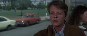 Movie still from “Casualties of War” (1989), directed by Brian De Palma – A man in a brown jacket and a red car in the background; Close Up shot, Over the shoulder angle