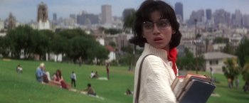 Movie still from “Casualties of War” (1989), directed by Brian De Palma – A woman in a white sweater and red scarf is standing in a park; Medium shot, Low angle