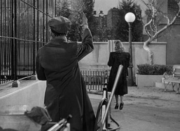 Movie still from “Cat People” (1942), directed by Jacques Tourneur – Two women are standing in front of a fence; Wide shot, Over the shoulder angle