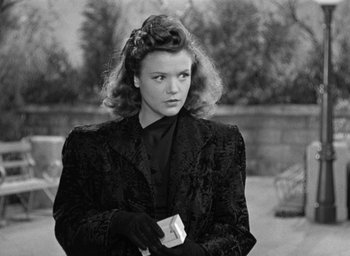 Movie still from “Cat People” (1942), directed by Jacques Tourneur – A black and white photo of a woman holding a box; Medium shot, Over the shoulder angle