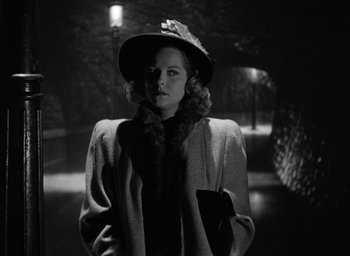 Movie still from “Cat People” (1942), directed by Jacques Tourneur – A black and white photo of a woman in a hat and coat; Medium shot, Low angle