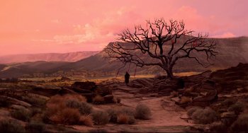 Movie still from “Cat People” (1982), directed by Paul Schrader – A person standing next to a tree in the middle of the desert; Extreme Wide shot, High angle