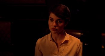 Movie still from “Cat People” (1982), directed by Paul Schrader – A woman in a white shirt is sitting in a dark room; Close Up shot, Over the shoulder angle