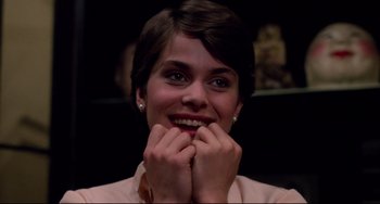 Movie still from “Cat People” (1982), directed by Paul Schrader – A person smiling with her hands on her face; Close Up shot, Low angle