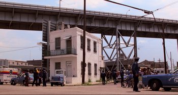 Movie still from “Cat People” (1982), directed by Paul Schrader – A group of people standing on the side of a road; Extreme Wide shot, High angle