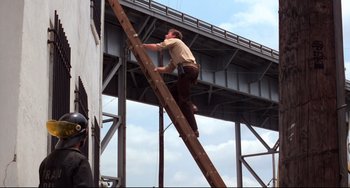 Movie still from “Cat People” (1982), directed by Paul Schrader – A man standing on top of a wooden ladder; Wide shot, Low angle