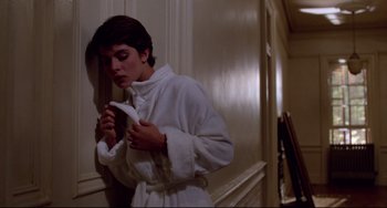 Movie still from “Cat People” (1982), directed by Paul Schrader – A woman in a white bathrobe is holding a paper; Medium shot, Low angle