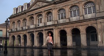 Movie still from “Cat People” (1982), directed by Paul Schrader – A man standing in front of a building in the rain; Extreme Wide shot, Low angle