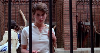 Movie still from “Cat People” (1982), directed by Paul Schrader – A woman standing behind a metal fence; Medium shot, Low angle