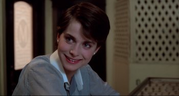 Movie still from “Cat People” (1982), directed by Paul Schrader – A woman with short brown hair smiles for the camera; Close Up shot, Over the shoulder angle