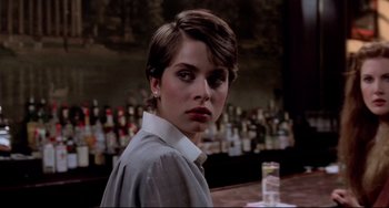 Movie still from “Cat People” (1982), directed by Paul Schrader – A woman in a white shirt is sitting at a bar; Close Up shot, Over the shoulder angle