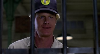 Movie still from “Cat People” (1982), directed by Paul Schrader – A person behind bars wearing a hat; Close Up shot, Low angle