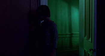 Movie still from “Cat People” (1982), directed by Paul Schrader – A woman standing in a room next to a wall; Medium shot, Over the shoulder angle