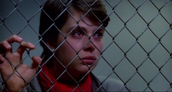 Movie still from “Cat People” (1982), directed by Paul Schrader – A young boy looking through a chain link fence; Close Up shot, Over the shoulder angle