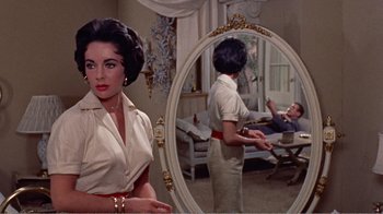 Movie still from “Cat on a Hot Tin Roof” (1958), directed by Richard Brooks – A woman standing in front of a round mirror; Medium shot, Over the shoulder angle