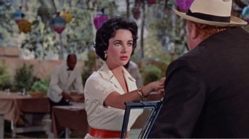 Movie still from “Cat on a Hot Tin Roof” (1958), directed by Richard Brooks – A woman in a white shirt and a red belt; Medium shot, Over the shoulder angle