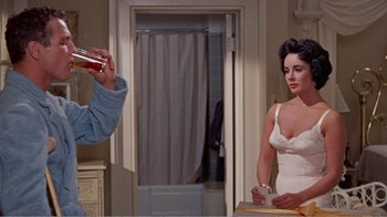 Movie still from “Cat on a Hot Tin Roof” (1958), directed by Richard Brooks – A man taking a picture of a woman in a white dress; Medium shot, Over the shoulder angle