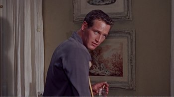 Movie still from “Cat on a Hot Tin Roof” (1958), directed by Richard Brooks – A man standing in front of a wall with pictures on the wall; Close Up shot, Low angle