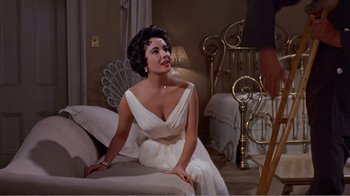 Movie still from “Cat on a Hot Tin Roof” (1958), directed by Richard Brooks – A woman in a white dress sitting on a couch; Medium shot, Low angle