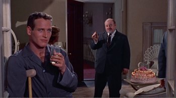 Movie still from “Cat on a Hot Tin Roof” (1958), directed by Richard Brooks – A man in a suit and tie standing next to another man in a suit and tie; Medium shot, Low angle