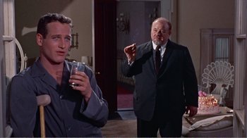 Movie still from “Cat on a Hot Tin Roof” (1958), directed by Richard Brooks – A man in a suit and tie holding a glass of water; Medium shot, Low angle