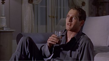 Movie still from “Cat on a Hot Tin Roof” (1958), directed by Richard Brooks – A man sitting on a couch holding a glass of water; Medium shot, Low angle