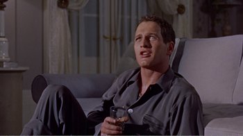 Movie still from “Cat on a Hot Tin Roof” (1958), directed by Richard Brooks – A man sitting on a couch holding a glass of wine; Medium shot, Low angle