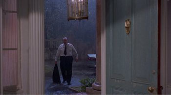 Movie still from “Cat on a Hot Tin Roof” (1958), directed by Richard Brooks – A man in a suit and tie walking through a door way in the pouring rain; Wide shot, Low angle