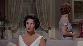 Movie still from “Cat on a Hot Tin Roof” (1958), directed by Richard Brooks – A woman sitting on a couch next to another woman; Medium shot, Over the shoulder angle