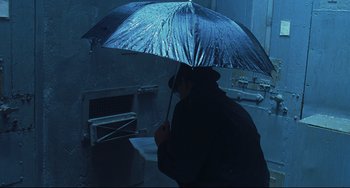 Movie still from “Catch Me If You Can” (2002), directed by Steven Spielberg – A person holding an umbrella in the rain; Medium shot, High angle