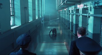 Movie still from “Catch Me If You Can” (2002), directed by Steven Spielberg – A man is kneeling down in a dark room; Wide shot, High angle
