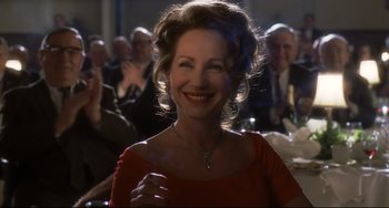 Movie still from “Catch Me If You Can” (2002), directed by Steven Spielberg – An older woman in a red dress smiling at the camera; Close Up shot, Over the shoulder angle