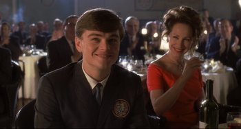 Movie still from “Catch Me If You Can” (2002), directed by Steven Spielberg – A man and a woman are smiling for the camera; Medium shot, Over the shoulder angle