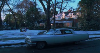 Movie still from “Catch Me If You Can” (2002), directed by Steven Spielberg – An old car parked in front of a house on a snowy day; Extreme Wide shot, Low angle